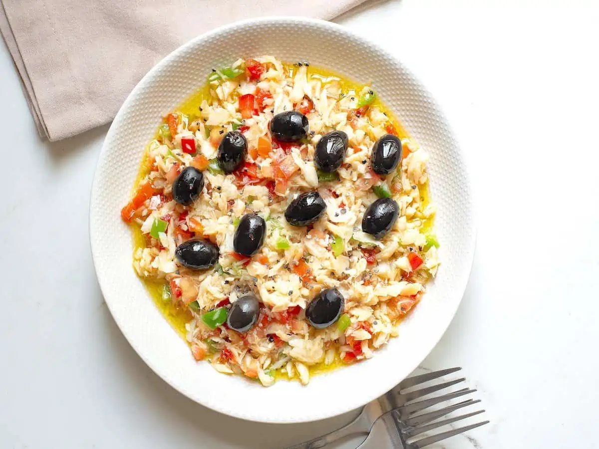 Overhead shot of esqueixada de bacalao catalana in a white plate with forks at the side.  