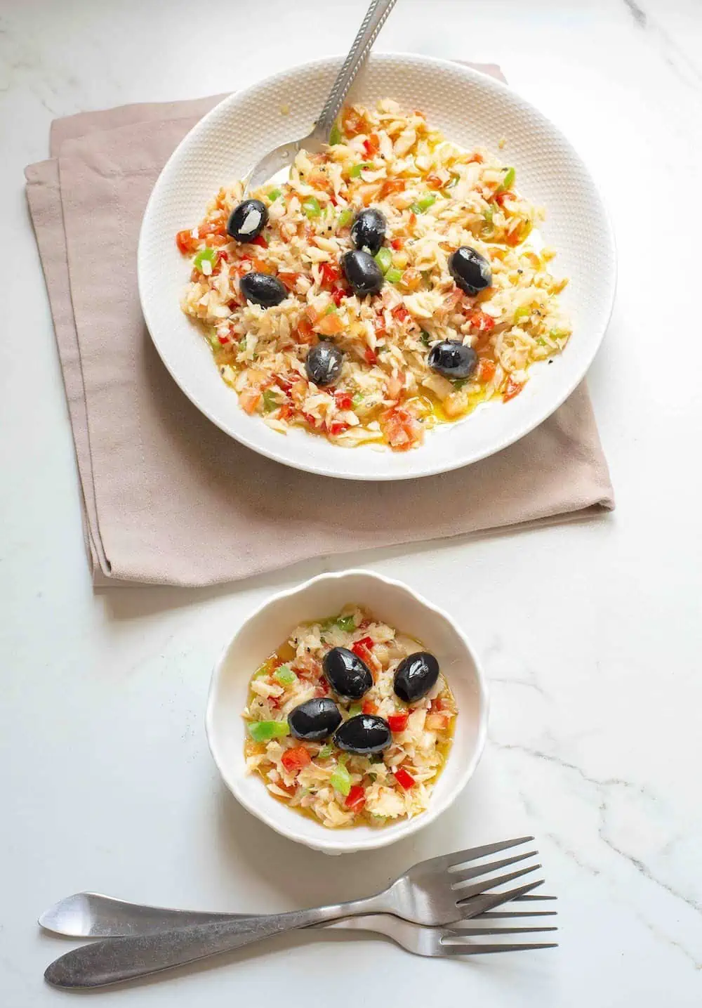 Esqueixada de Bacalao or Catalan Salt Cod Salad in a white bowl with a tapas serving and two forks. 