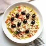 Esqueixada de Bacalao (Catalan Salt Cod Salad) in a white bowl on a beige napkin.