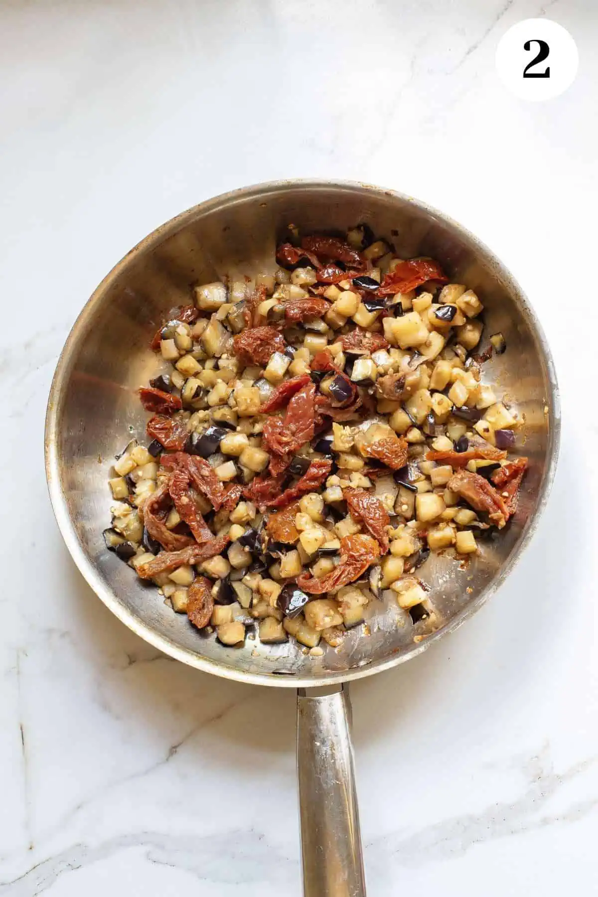 Sundried tomatoes and other ingredients added to the skillet with the eggplant.