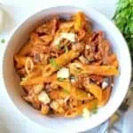 Pasta with eggplant and sundried tomatoes served in a white bowl.