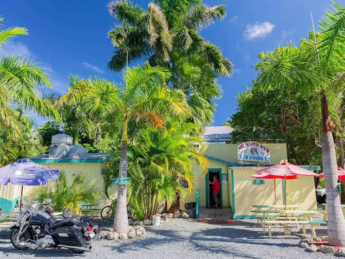 Beach bar with trees and motorcycle.