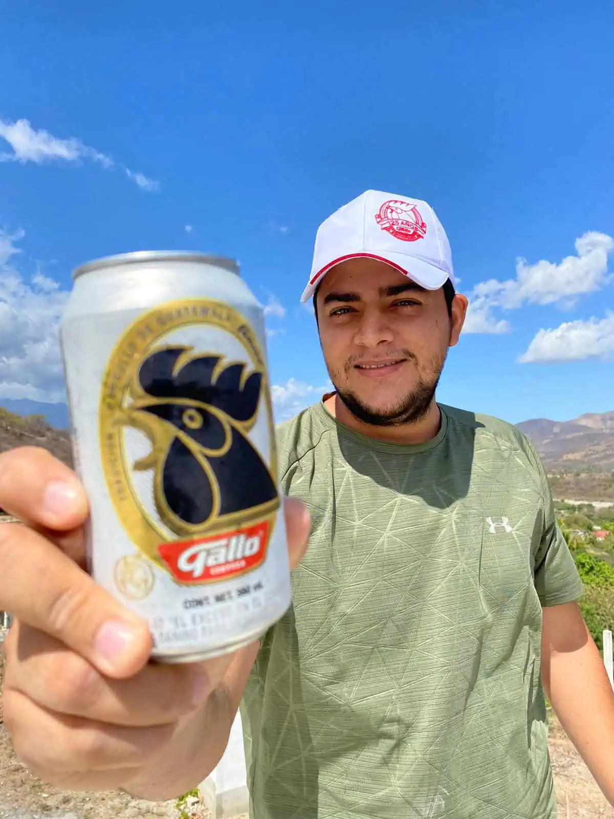 Guatemalan man holding a Gallo beer in the countryside.