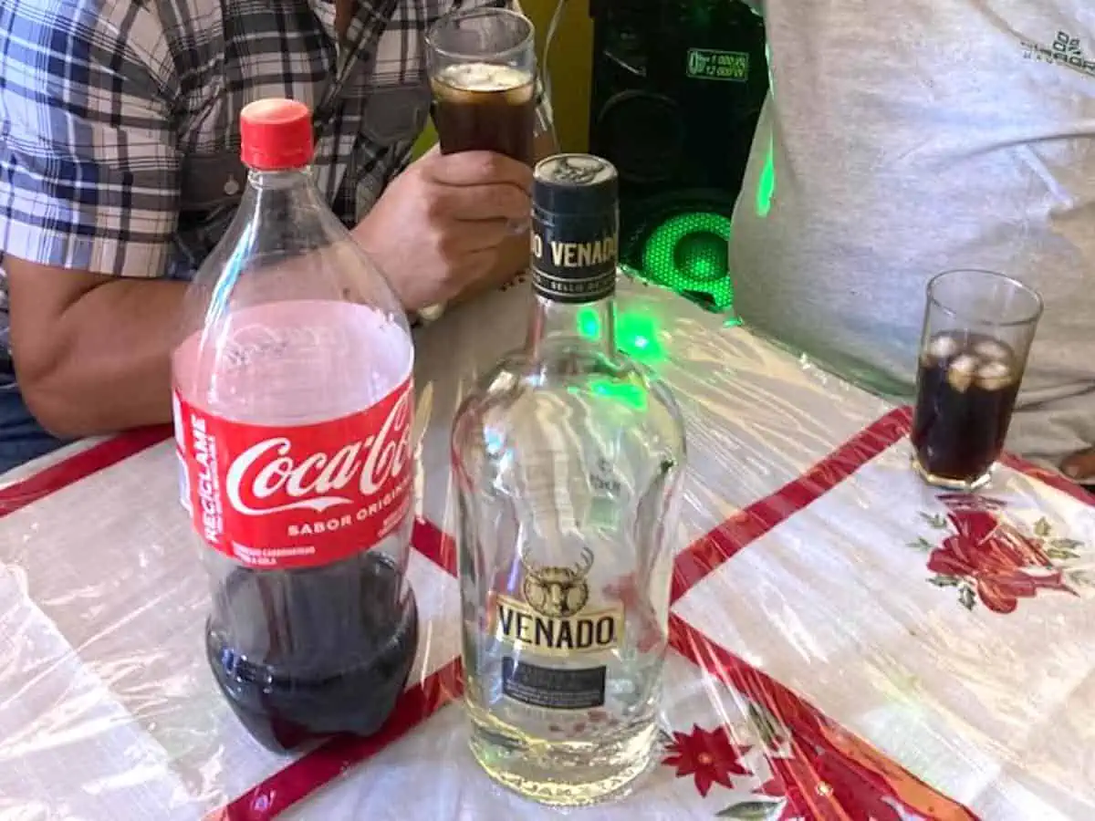 A bottle of the popular Guatemalan drink Venado Especial Rum on a table with a bottle of Coca Cola. 