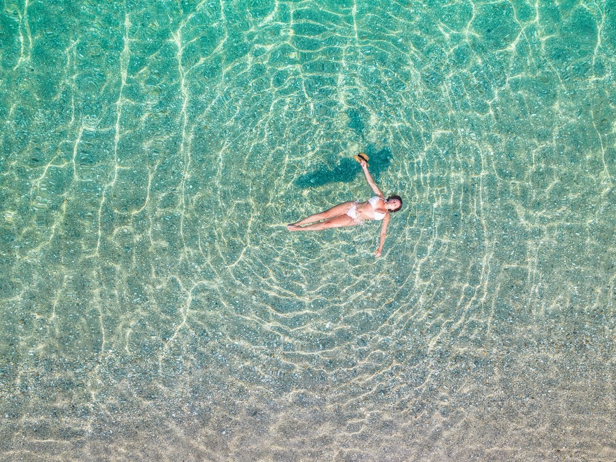 A woman floating in crystal-clear waters of the Mediterranean. 