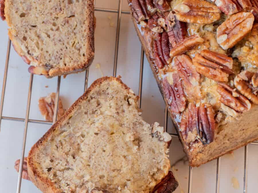 Banana pecan bread loaf next to some pieces sliced and laying flat.