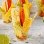 Fruit cups with pepitoria on a table with limes cut in half.